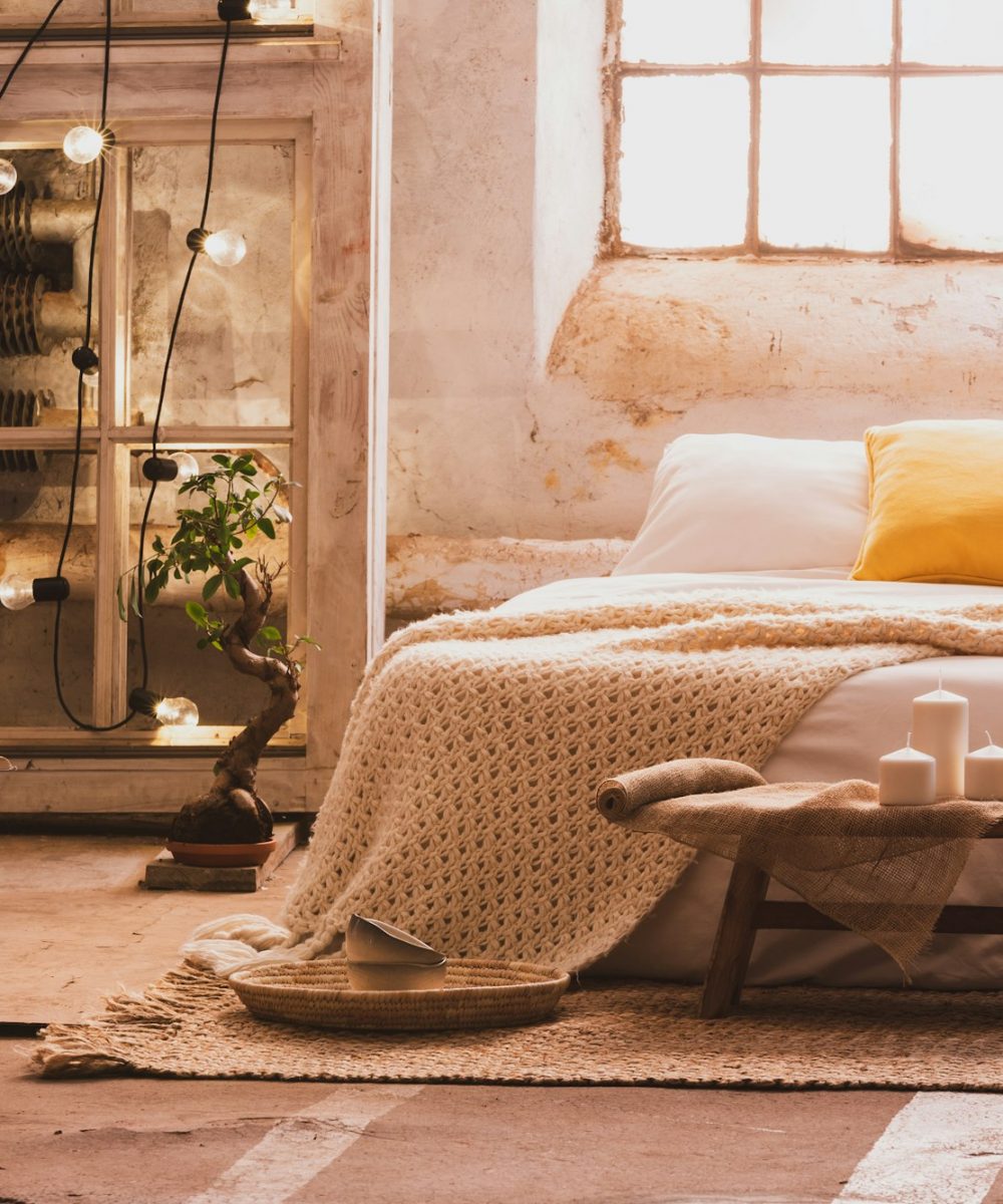 Cozy bedroom interior with a bed, stool, candles and industrial