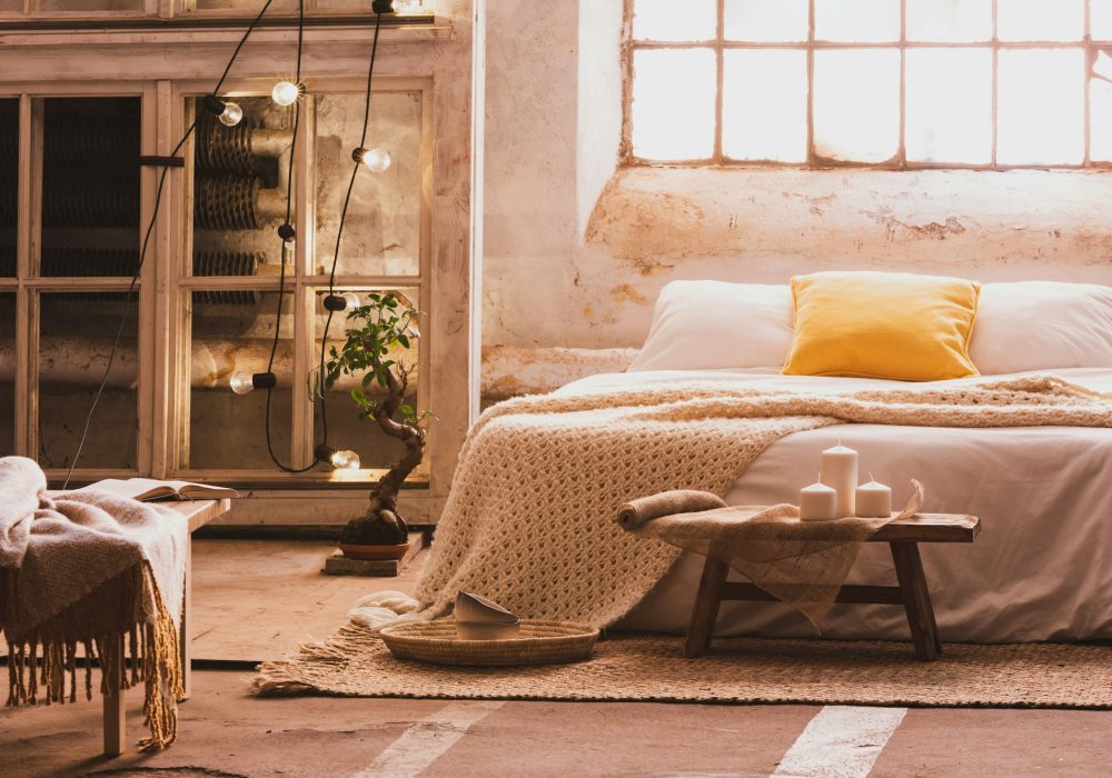 Cozy bedroom interior with a bed, stool, candles and industrial