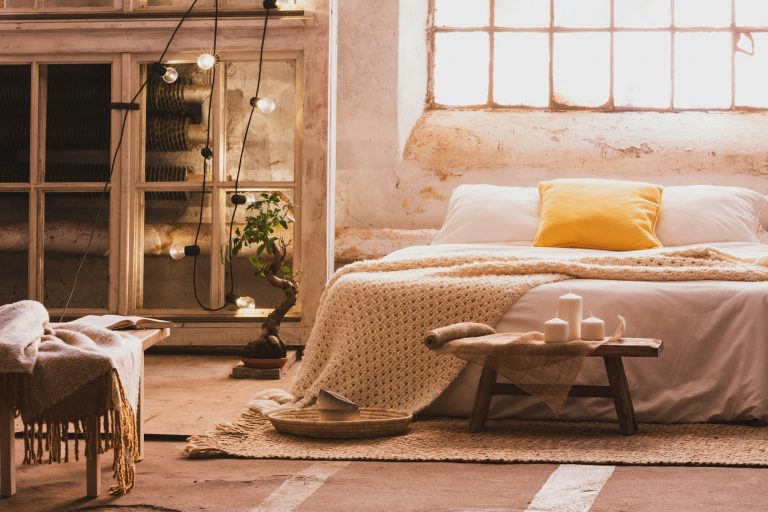 Cozy bedroom interior with a bed, stool, candles and industrial