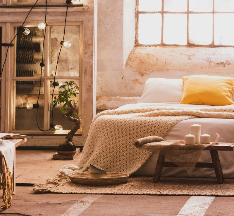 Cozy bedroom interior with a bed, stool, candles and industrial